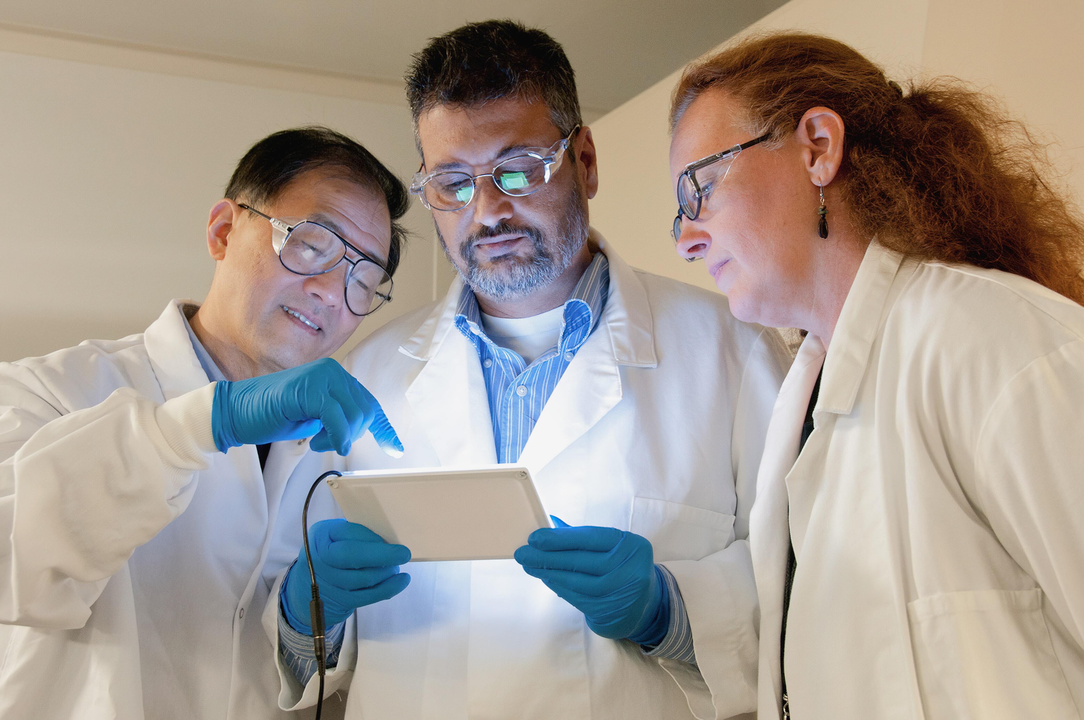 Three scientists looking at an electronic tablet
