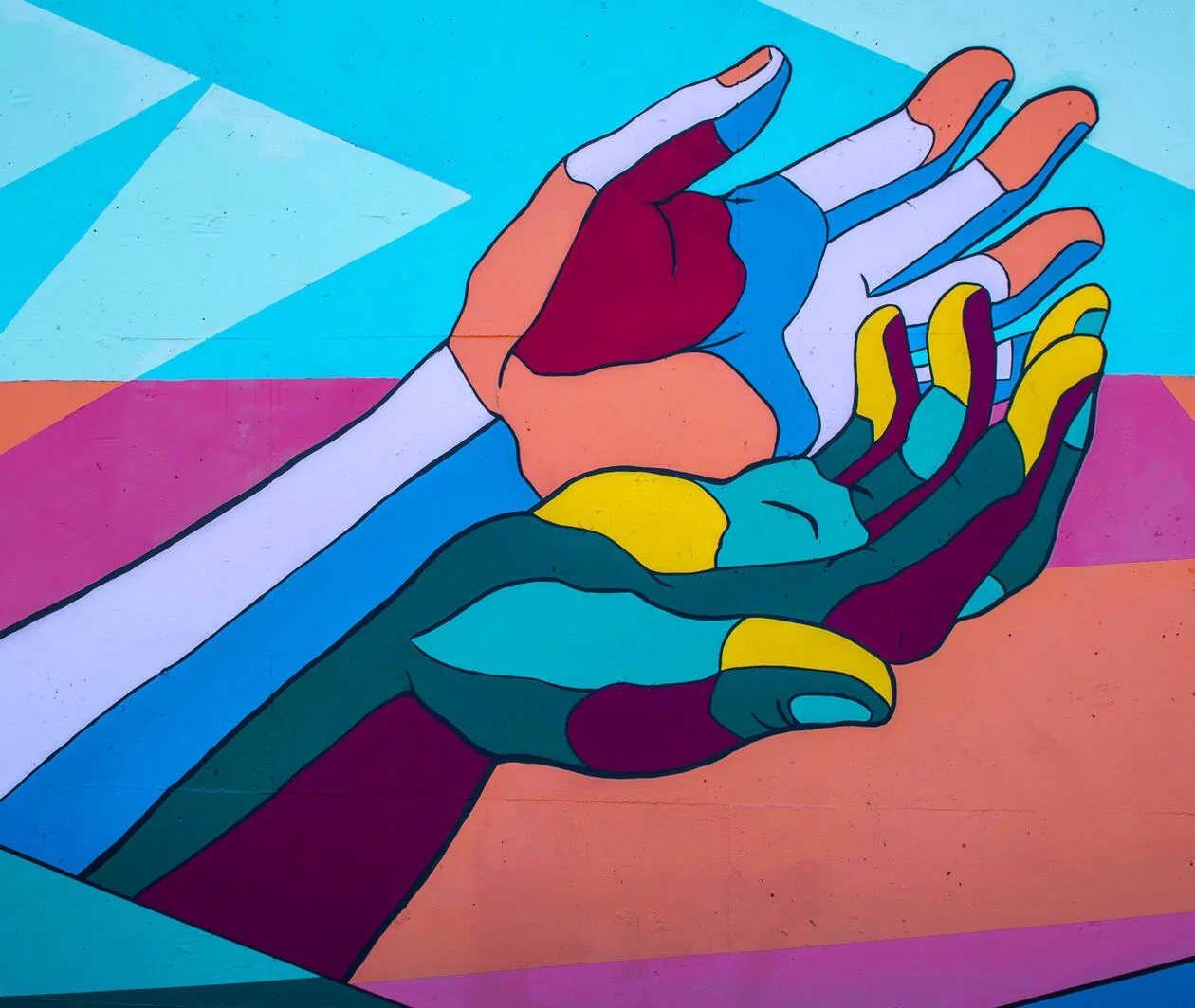 Artwork on the side of a building showing cupped multicoloured hands