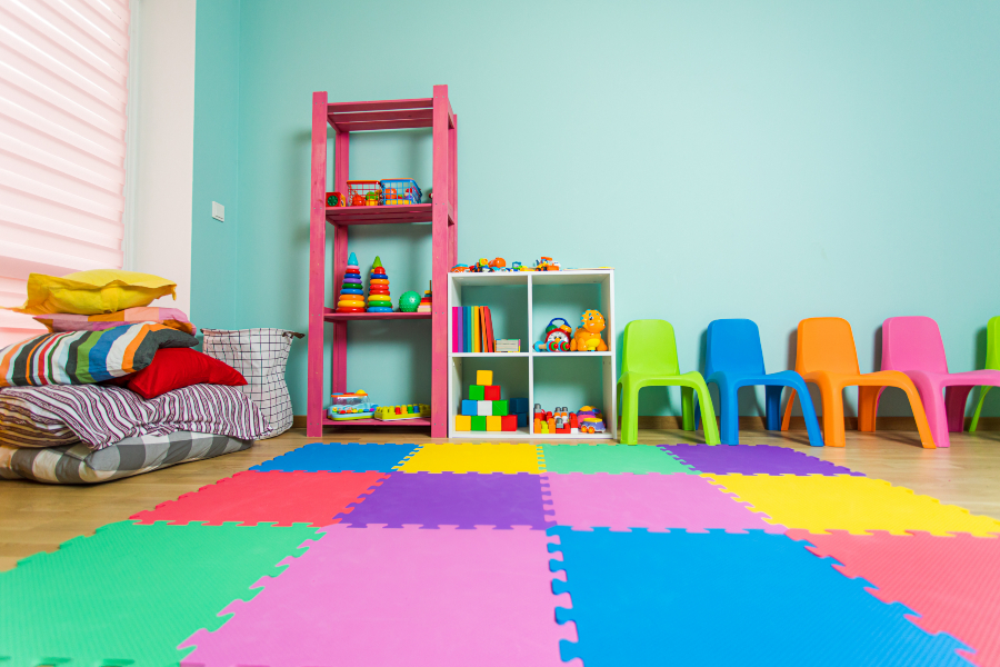 A wonderful infants room for learning a development. Floors are padded with coloured styrofoam jigsaw pieces and colourful toys and chairs up agaisnt the wall.