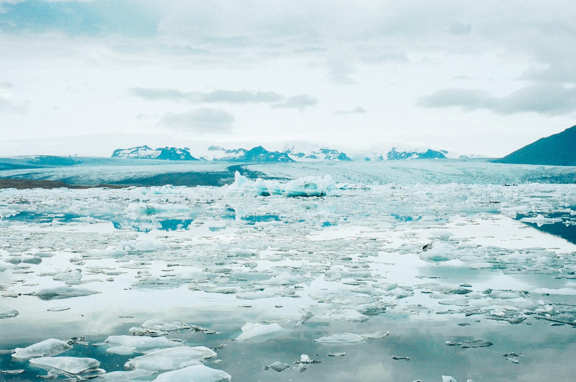 View over an expanse of water with fragmented broken ice against a backdrop of icy mountains