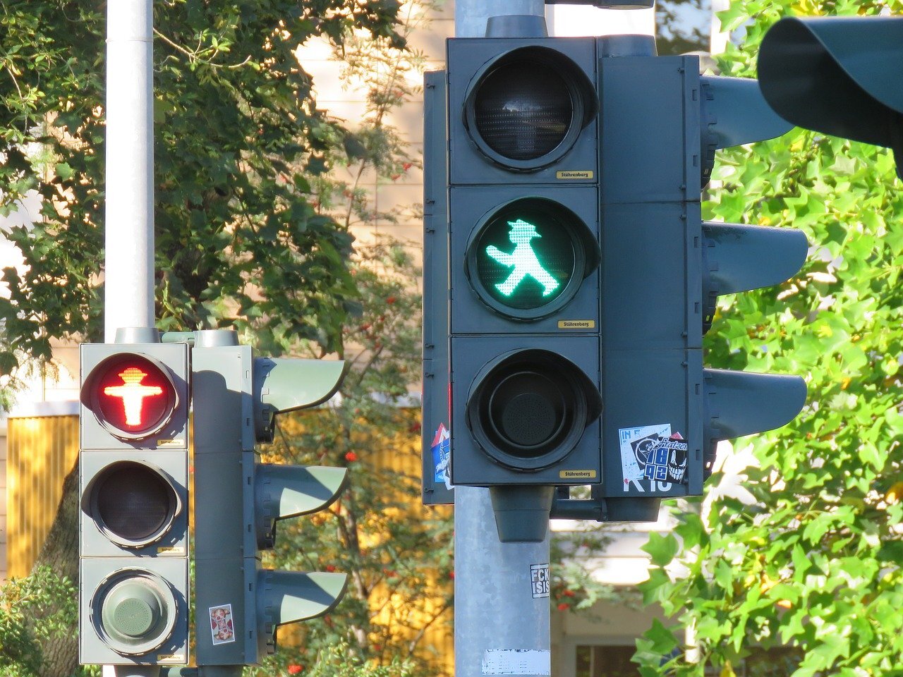 Two sets of pedestrian crossing lights, both apparently for the same crossing, one is green for go, but the other is red for stop