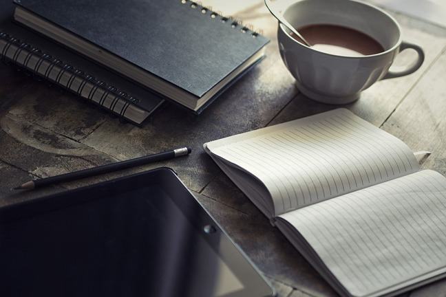 Image of a notepad, ipad and coffee on a desk