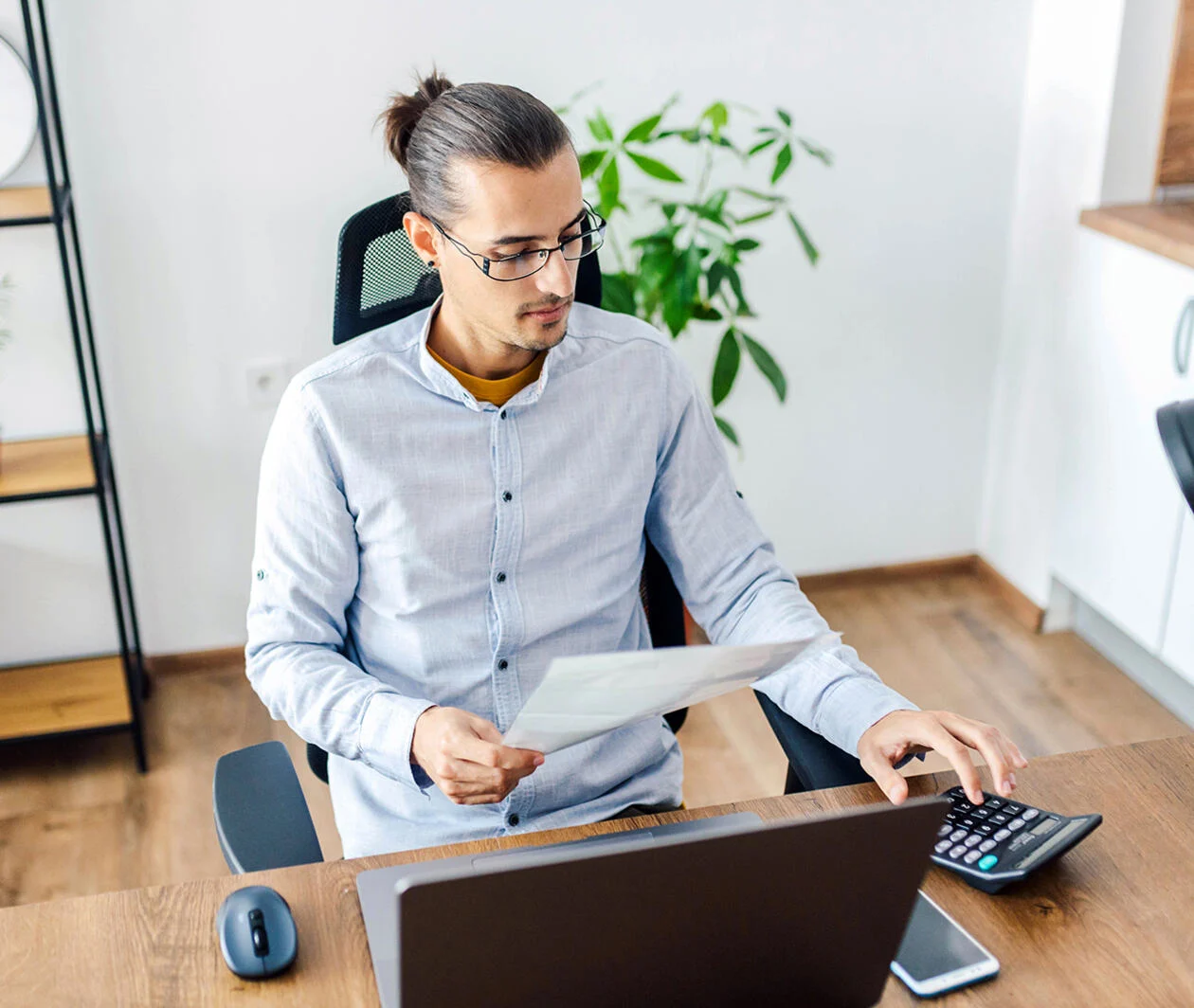 Man in office working with computer and calculator on a desk