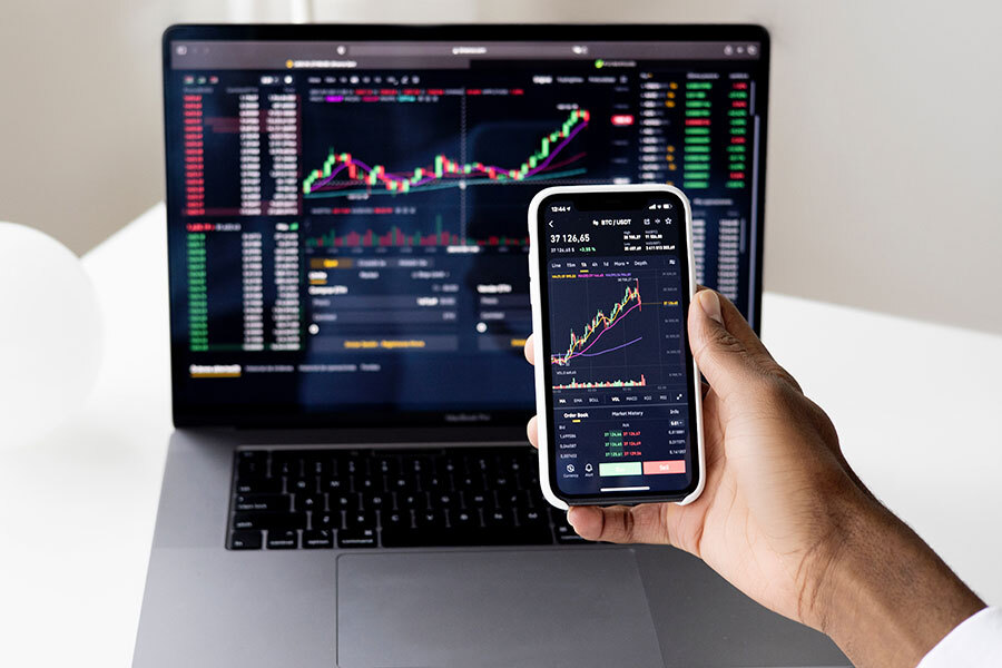 Computer and phone showing stock charts