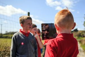 A boy holds up an iPad to film other school children.