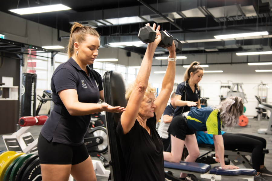 Lady lifting weights with trainer