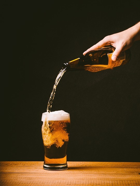 Pouring a bottle of beer into a pint glass.