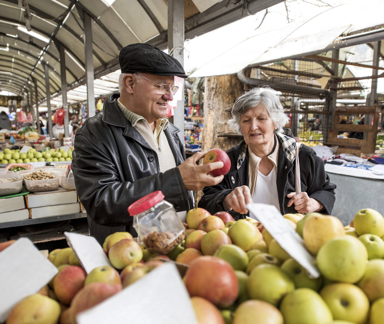 A man and woman buying fruit from a market stall