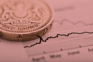 A coin sits on top of a line graph on a piece of paper – a metaphor for the financial services industry.