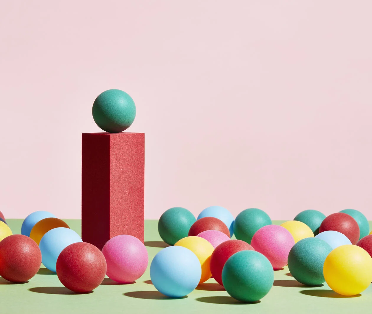 A green sphere stands on top of a pedestal surrounded by a crowd of multicoloured spheres to represent ethical leadership.