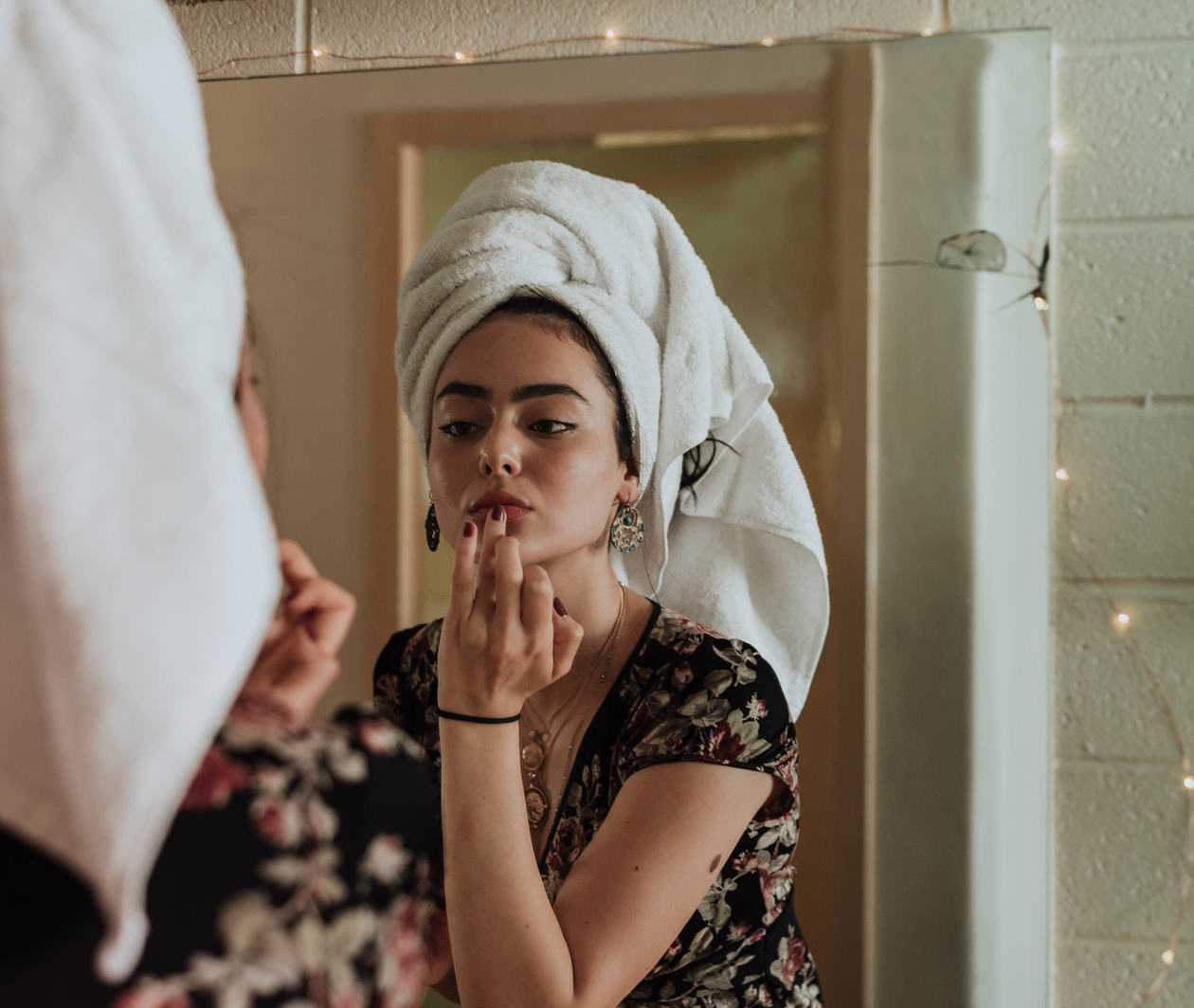 Woman putting on lip balm in the mirror