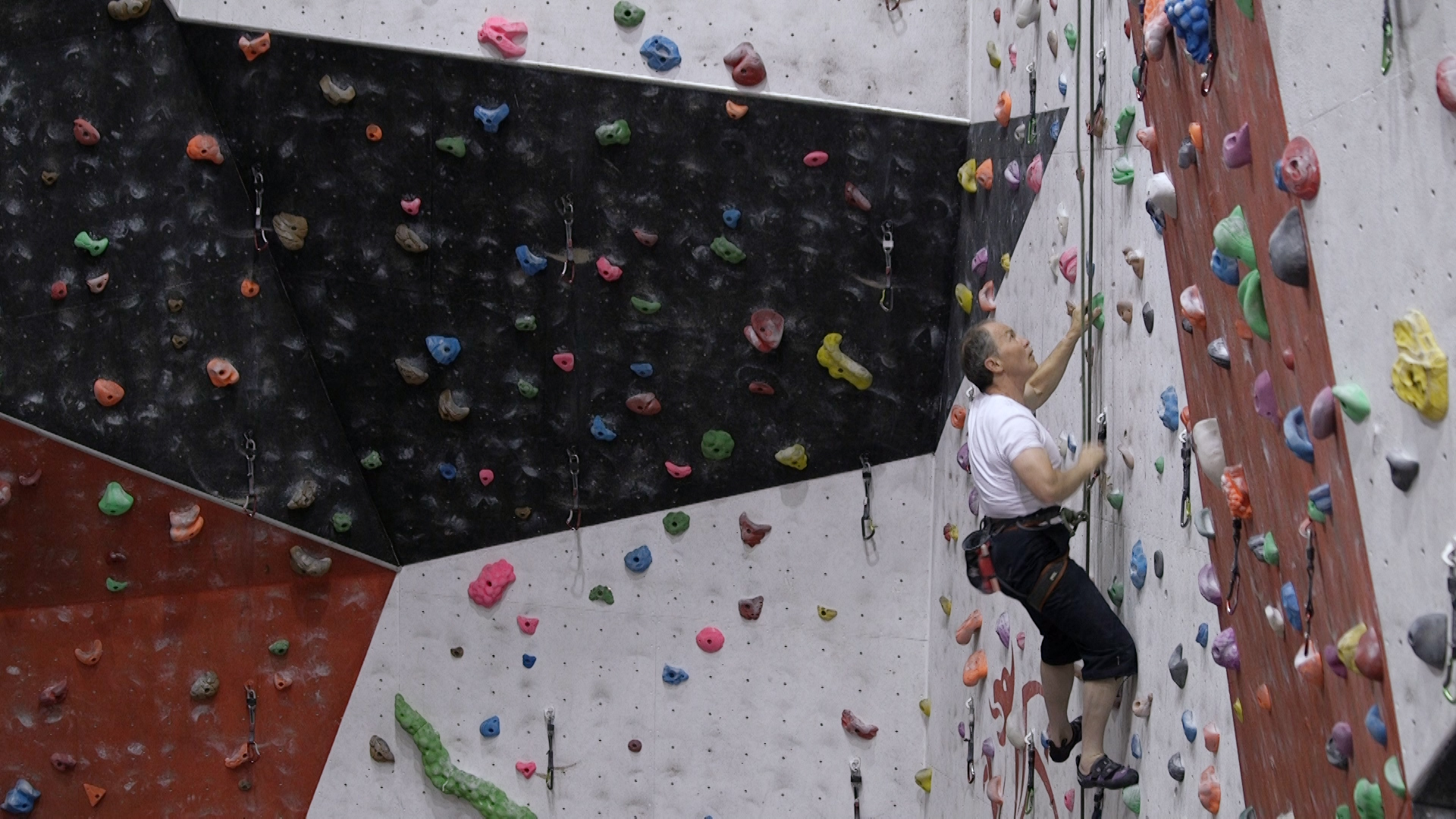 An older person at a climbing wall