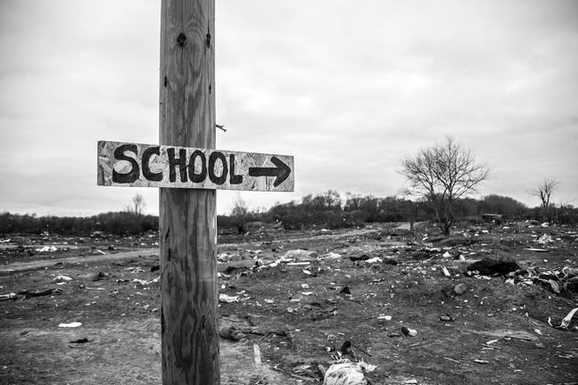 Sign indicating where the school is posted on a wooden pole