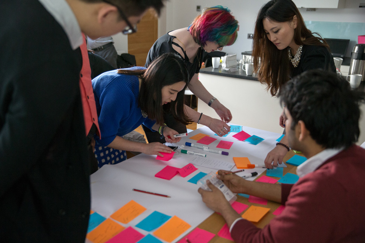 Students with multi coloured post it notes on table