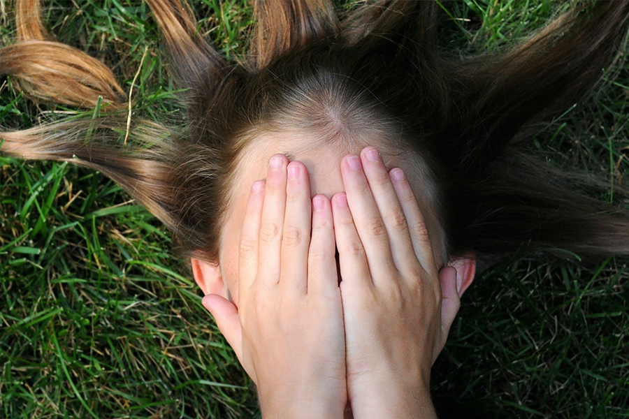 A young girl covering her face with her hands