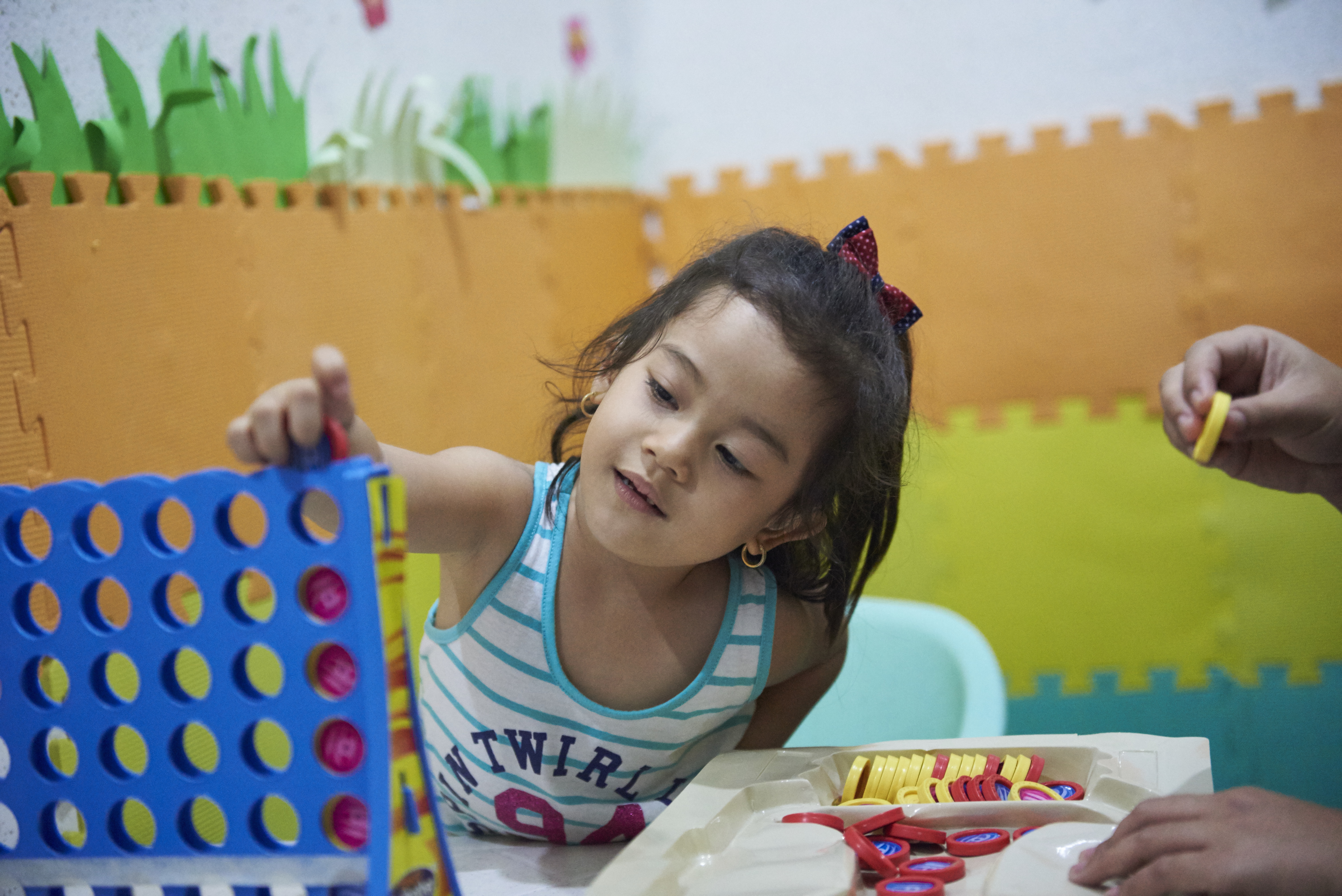 A girl with a hearing impairment playing a game of 'Connect Four'.