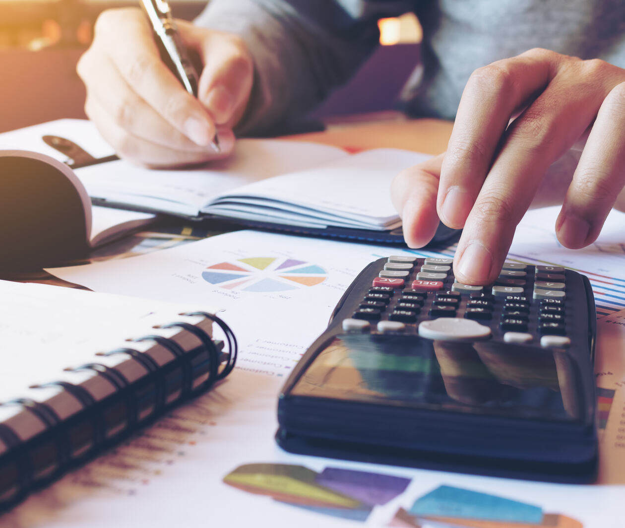 Man doing finances with a calculator at a desk.