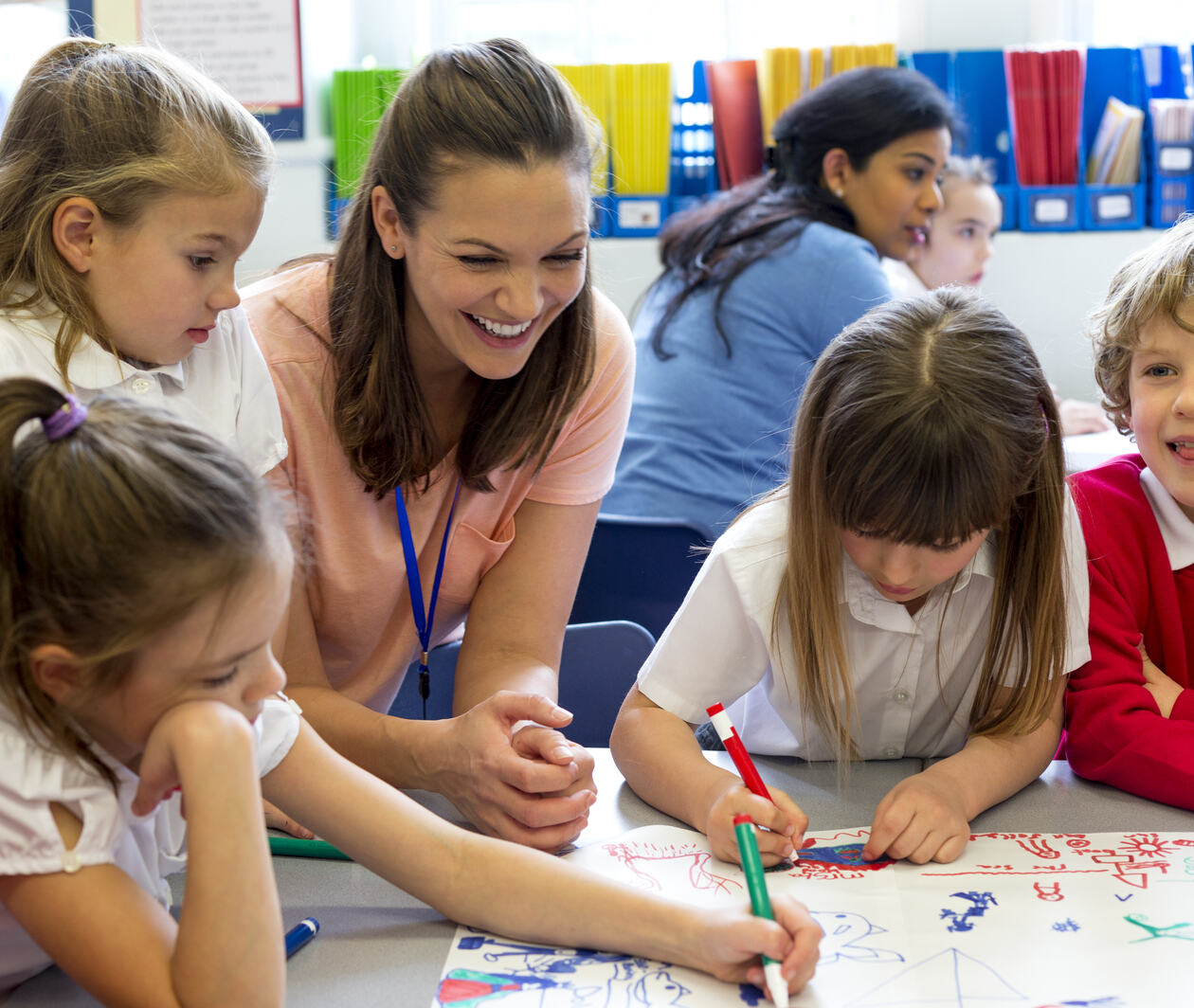 a teacher with a group of primary pupils happily working around a table