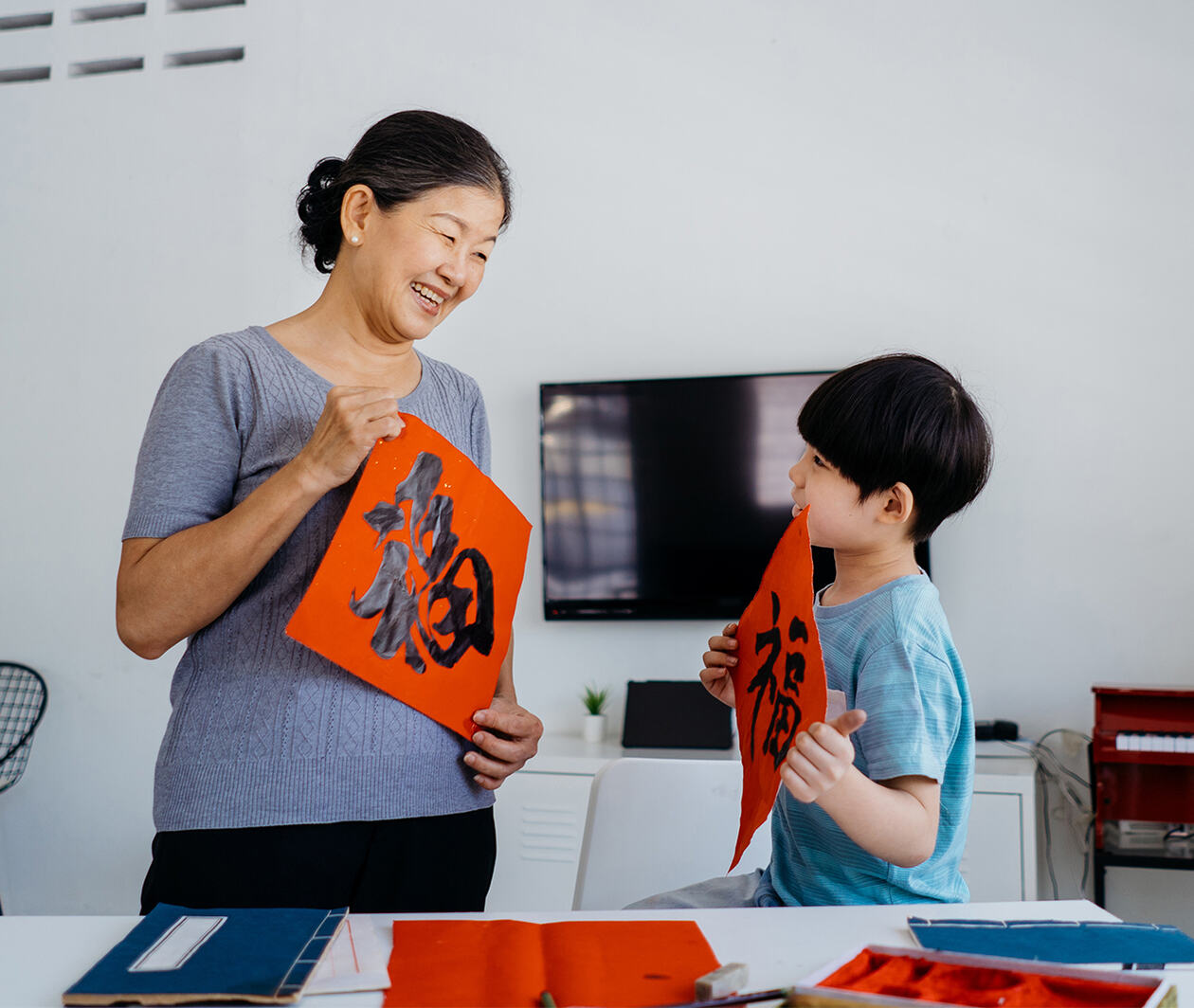 Senior asian woman writing chinese calligraphy with her grandson