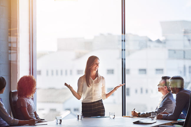 Woman standing up in meeting explaining her ideas