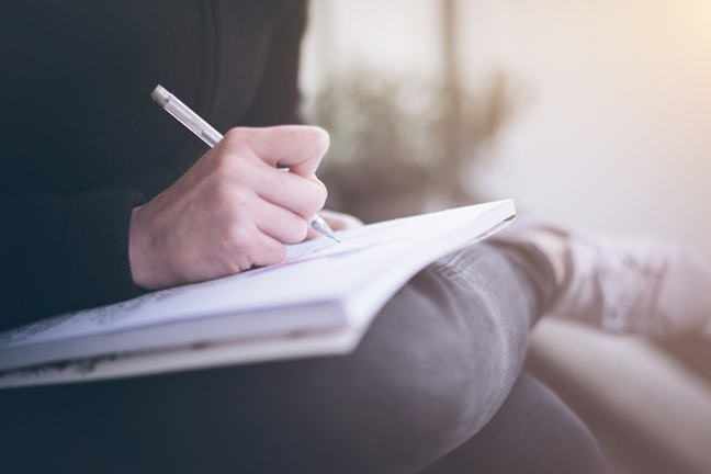 Close-Up Of Person Writing In Book