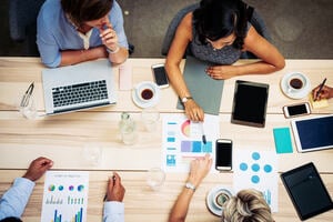 Group of entrepreneurs and business people sitting at the table with laptops, tablets, charts and graphs on it