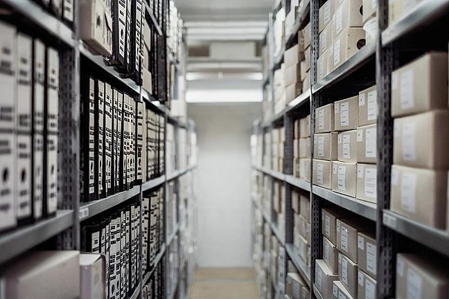 Boxes and ring binders stacked on shelves