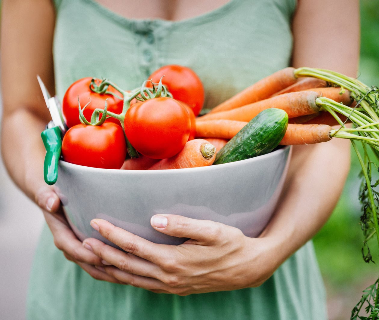 Woman standing with large bowel of fresh vegetables.