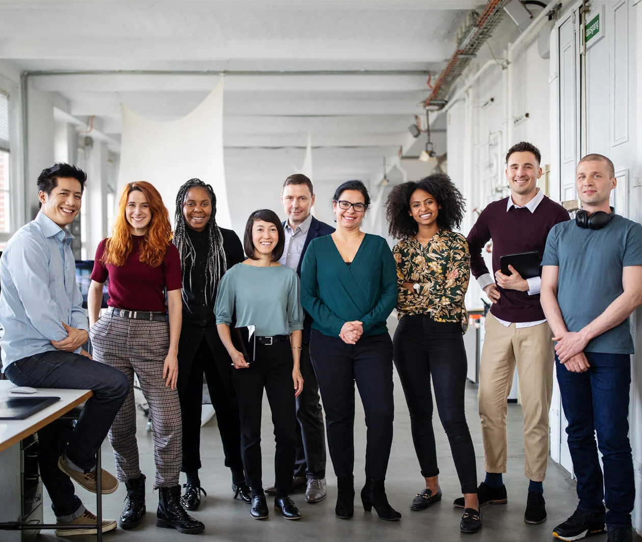 Multi-ethnic business group standing together in the office. Portrait of successful business professionals in an open plan office.