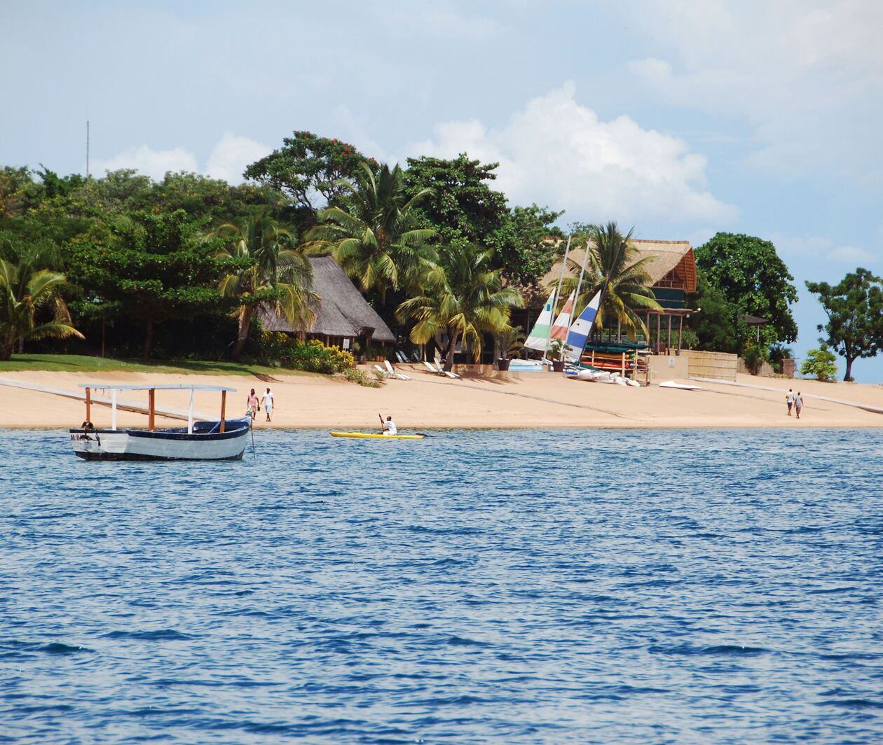 Malawi beach white boat on sea near palm trees