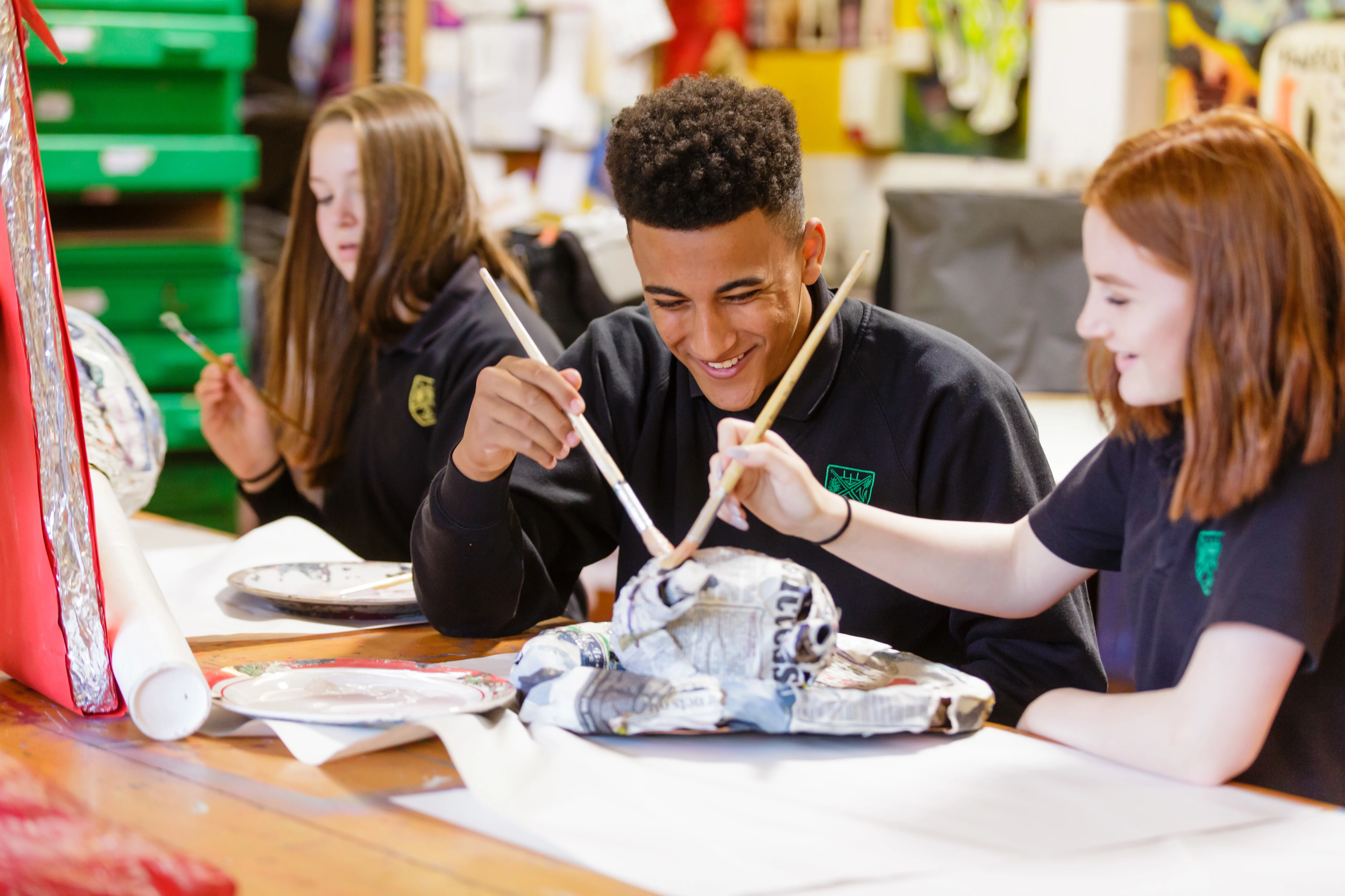 A photo of 2 students painting together in a classroom