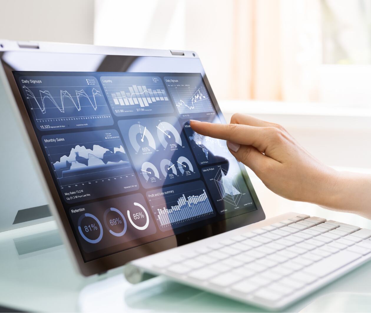 A lady touches a white tablet device screen with her finger in a kitchen setting.