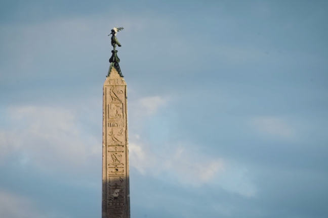 A photo of an obelisk that has a bird sitting on the top