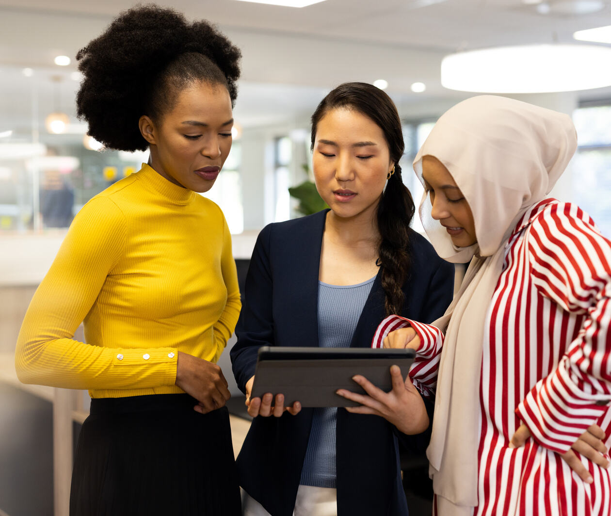 Three women discussing work at with a tablet
