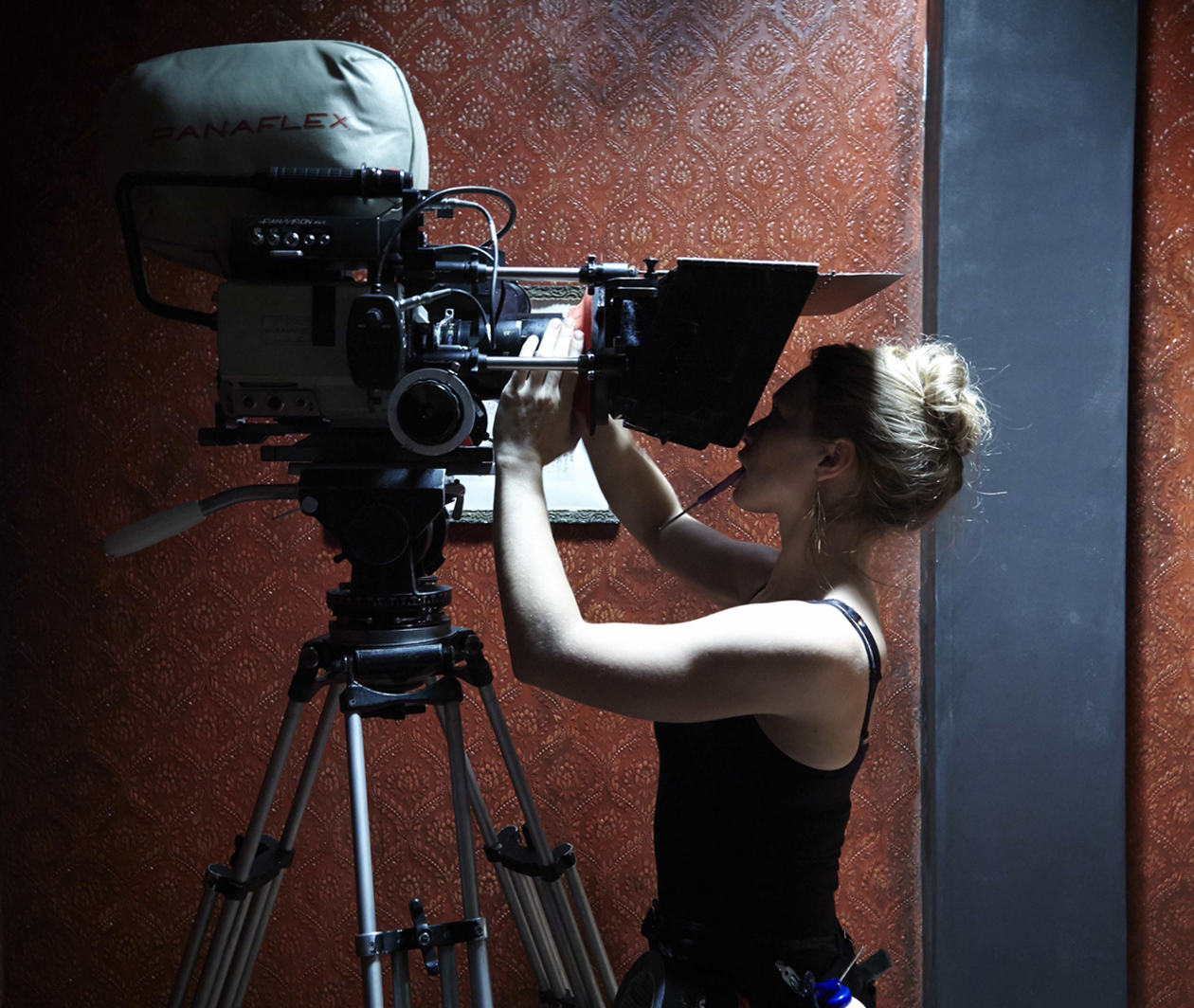 Filmmaking: a female cinematographer changing the lens on the camera