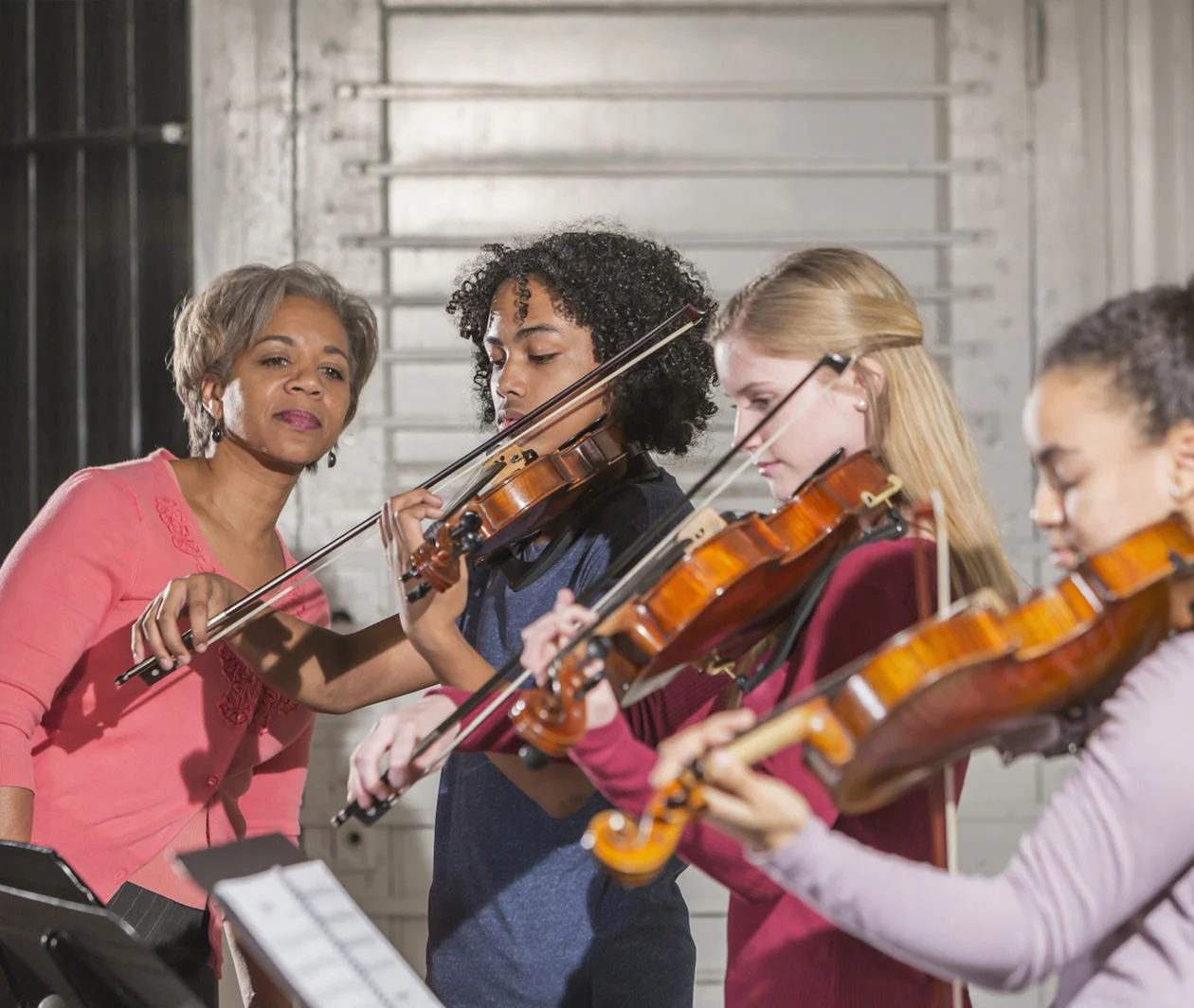 Image showing female violin teacher instructing three young students