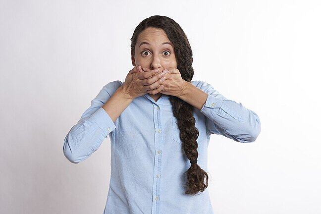 A woman holds her hands over her mouth as if thinking ‘I shouldn’t say this’