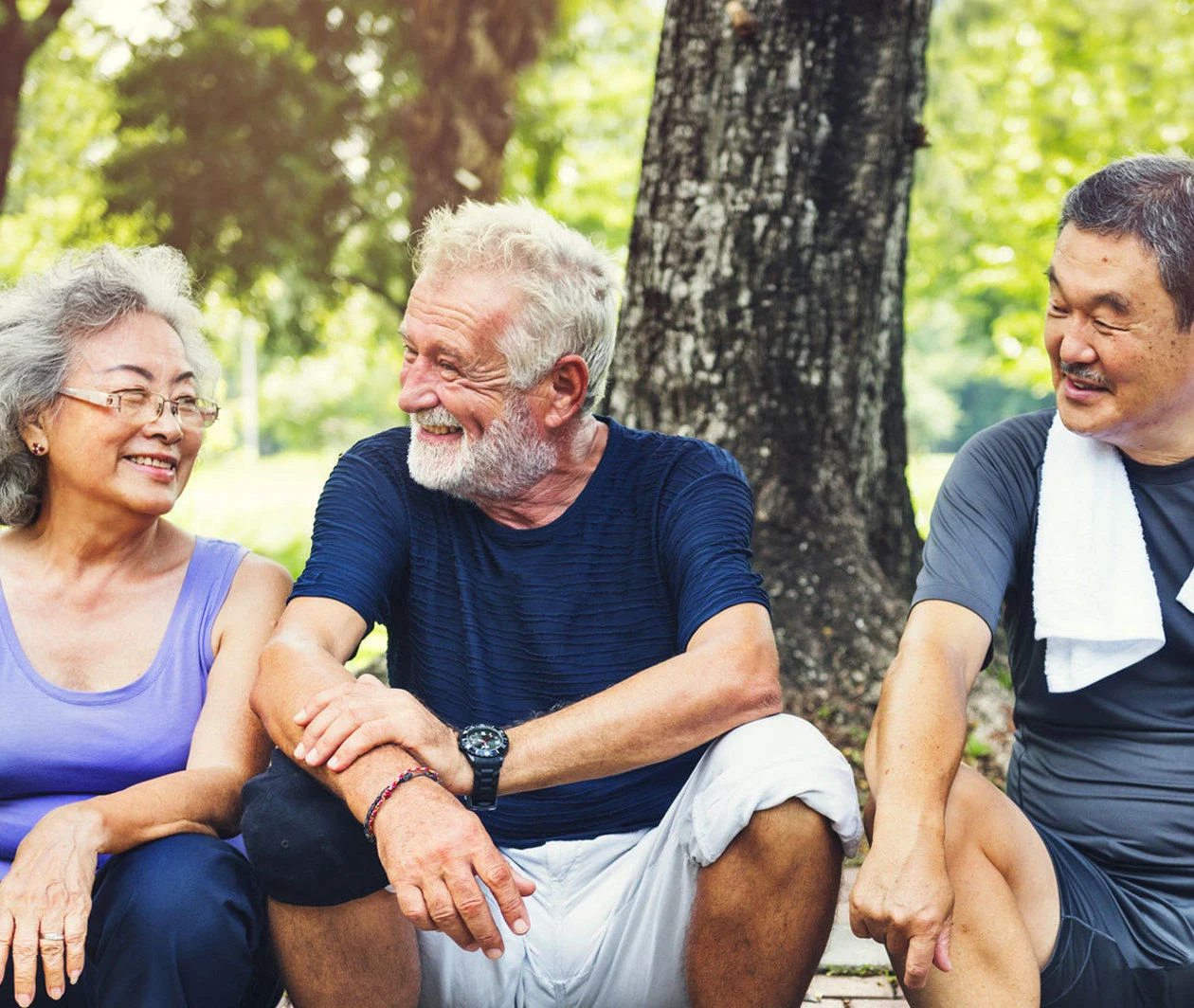 Three happy looking older people talking and resting after exercising