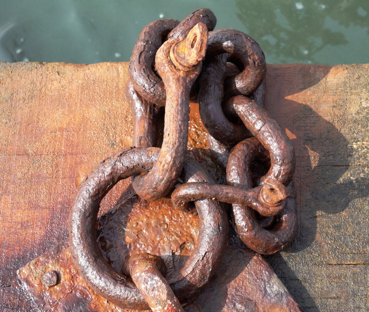 A steel chain appearing as a knot, showing signs of corrosion and material loss.