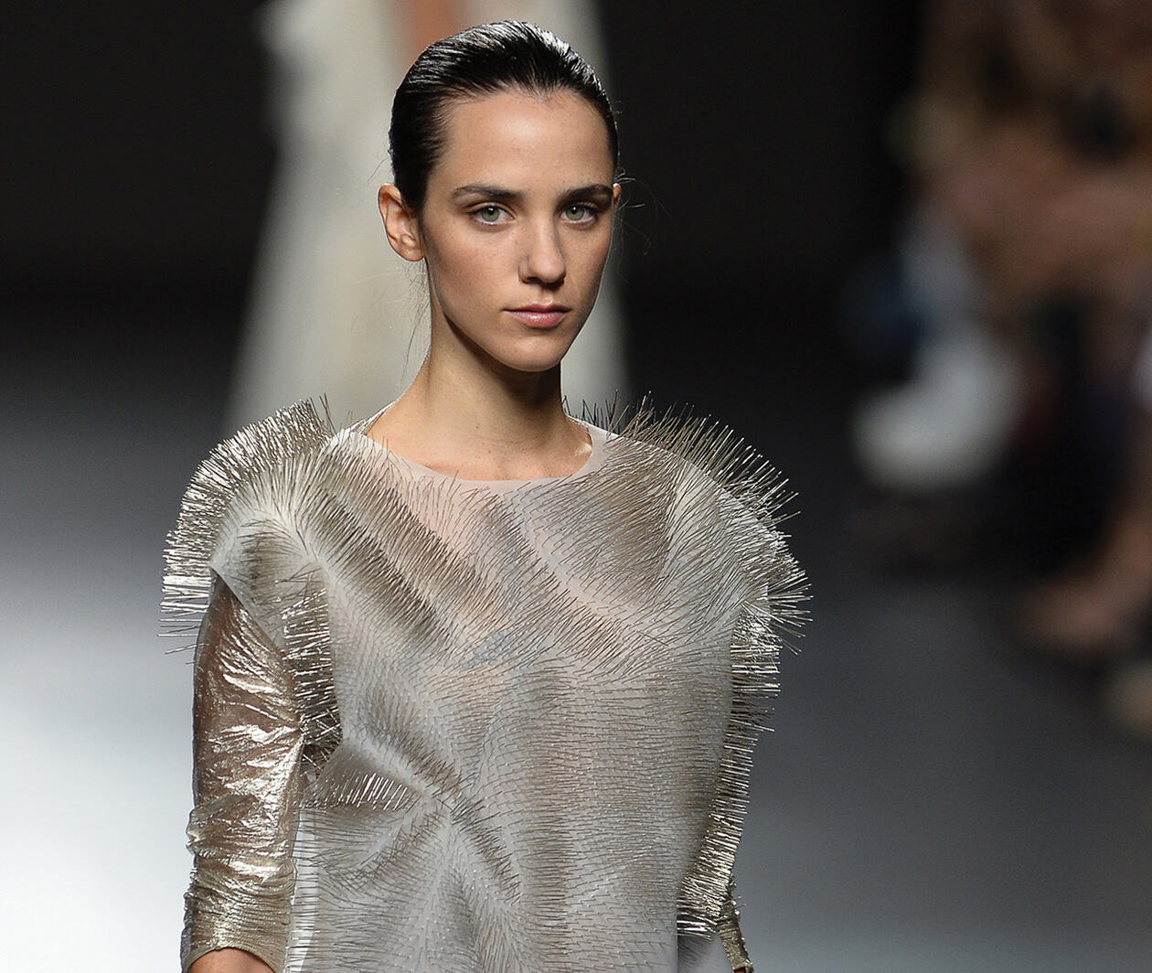 A model wearing a grey dress poses on the catwalk.