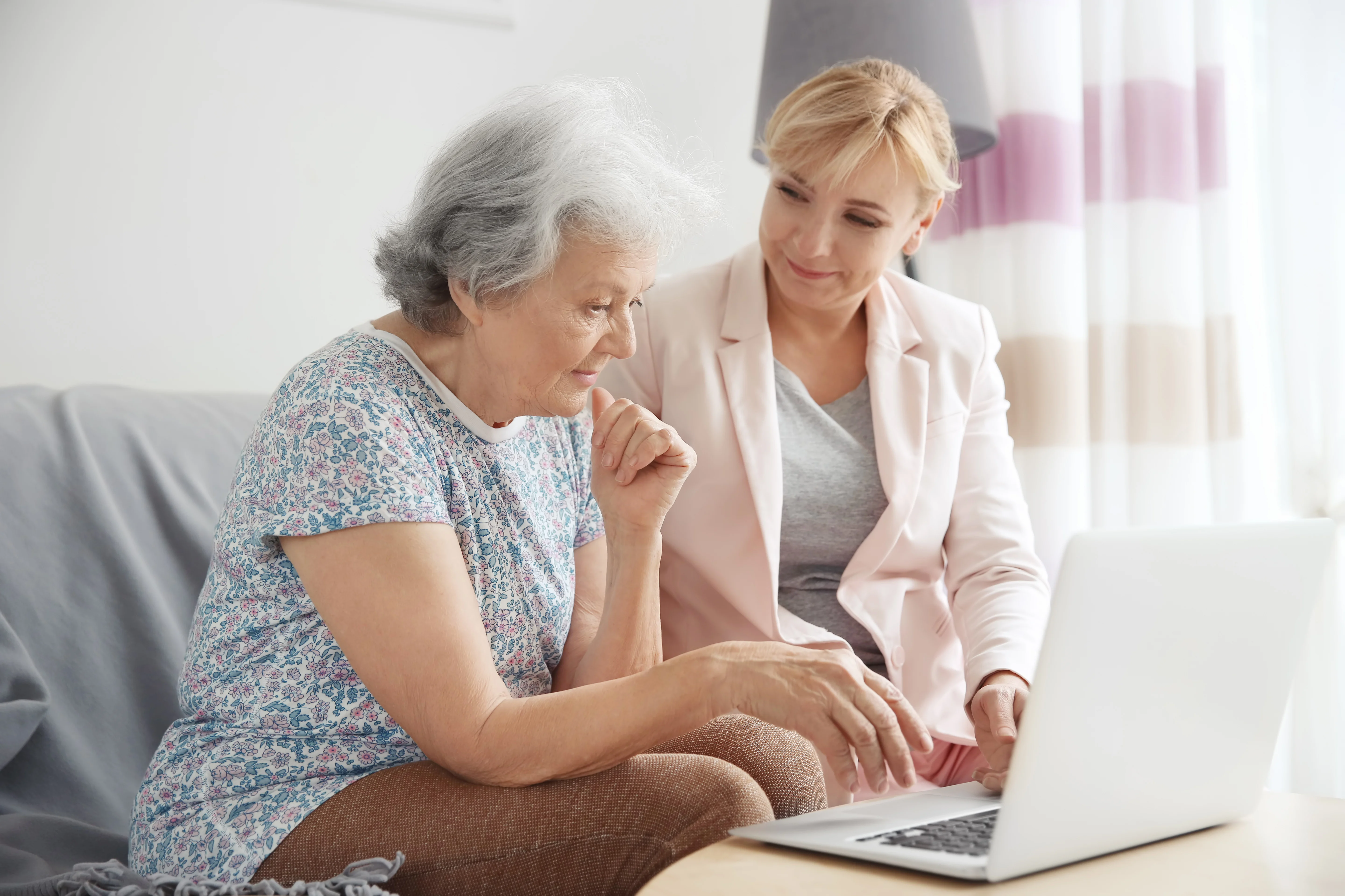 An older woman uses a laptop with a younger woman next to her