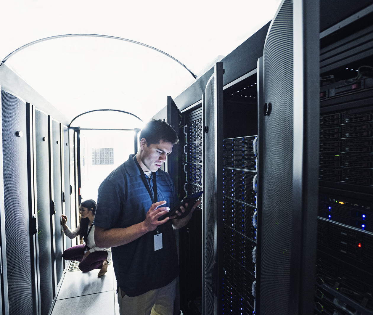 Technician standing in server room with a tablet.