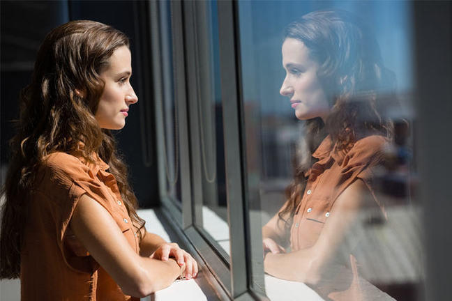 Woman looking out window, reflecting.