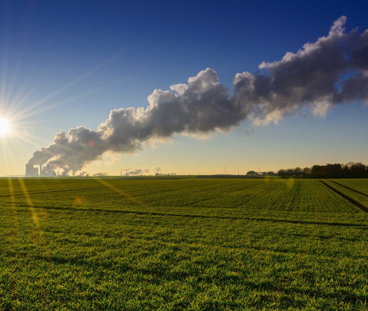 Factory emitting gasses with fields and trees