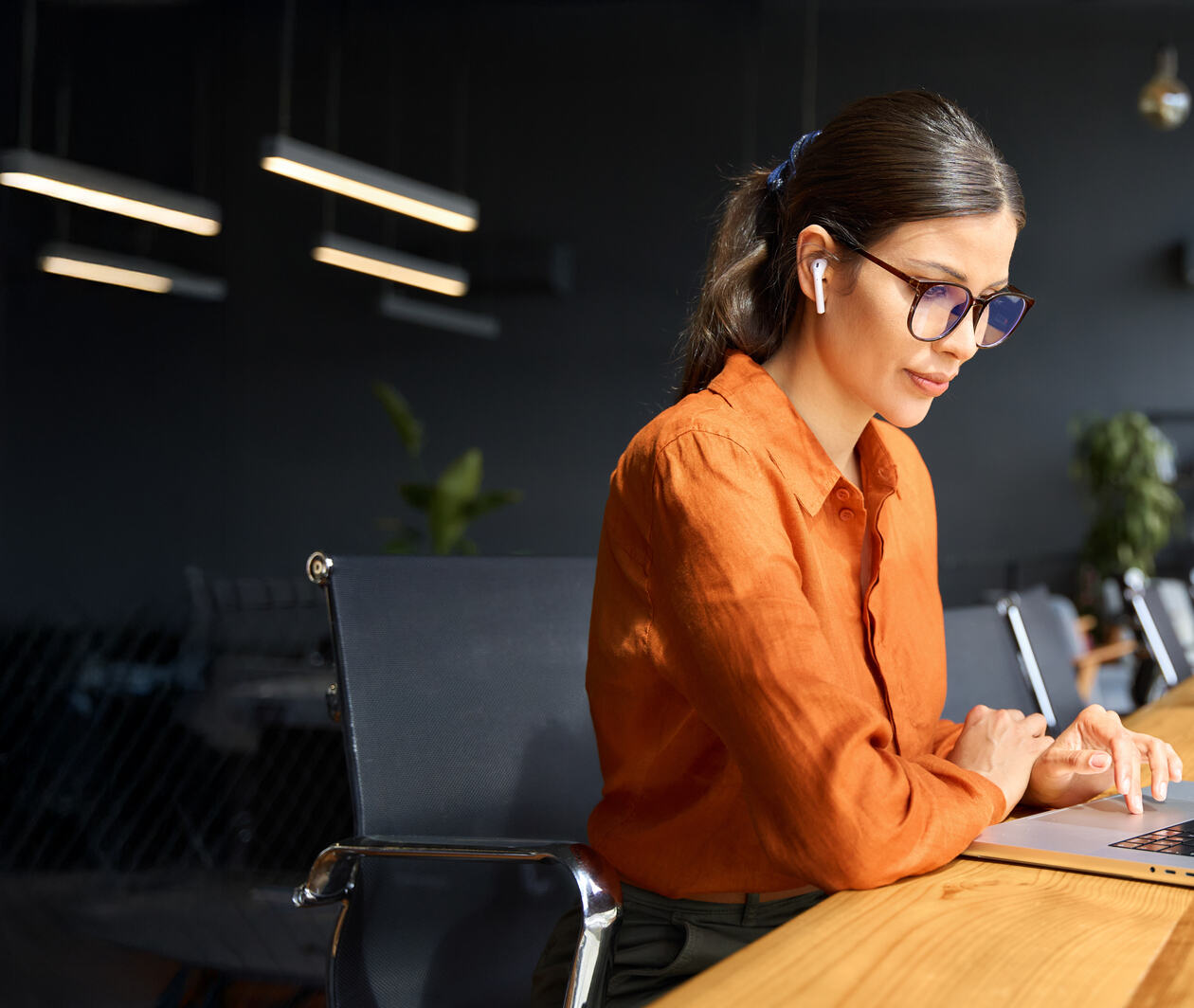 Latin hispanic young business woman working on laptop computer at office desk with city view. Indian entrepreneur manager businesswoman using pc for work, learning at workplace.