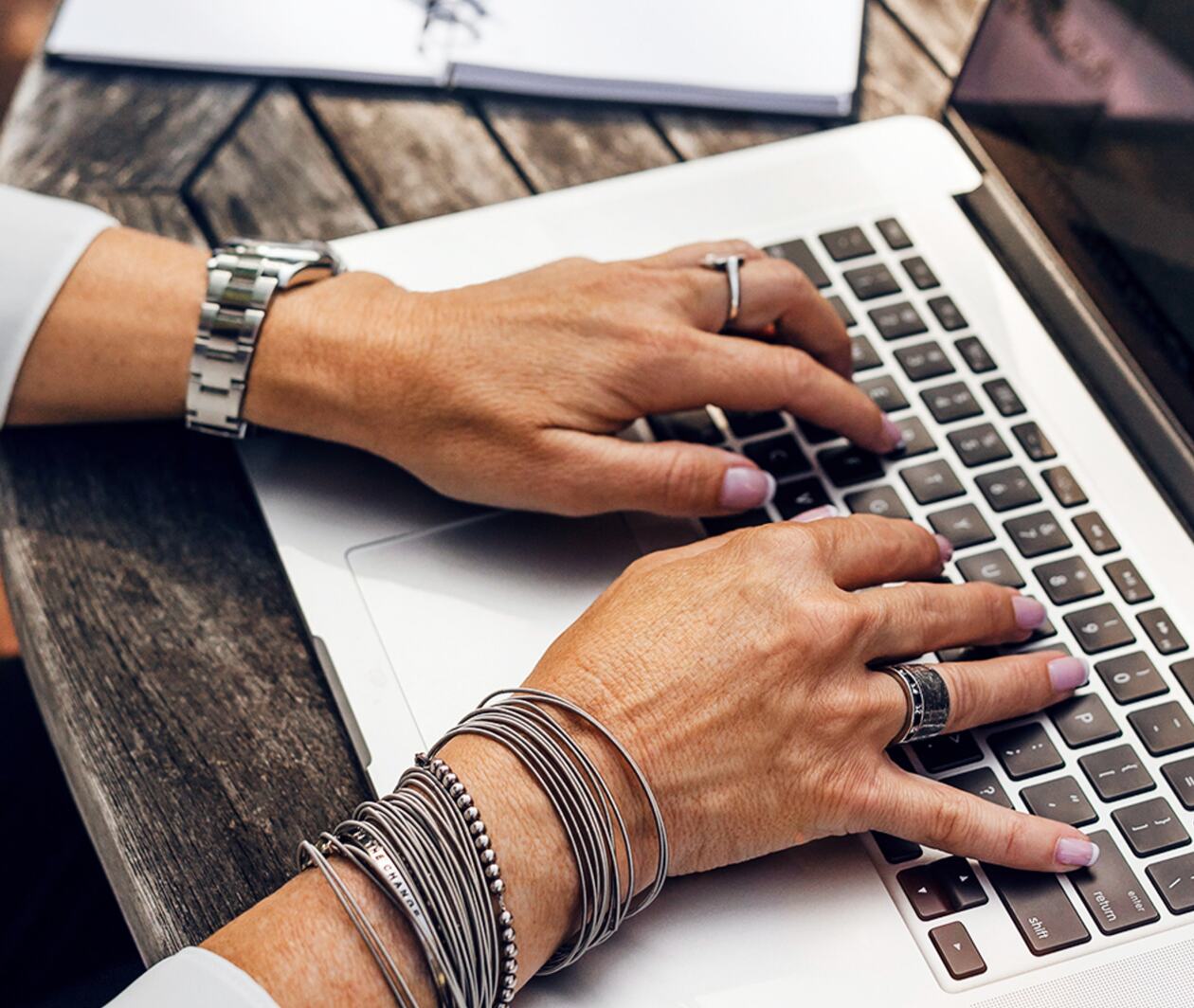 The hands of a person typing on a laptop keyboard. 