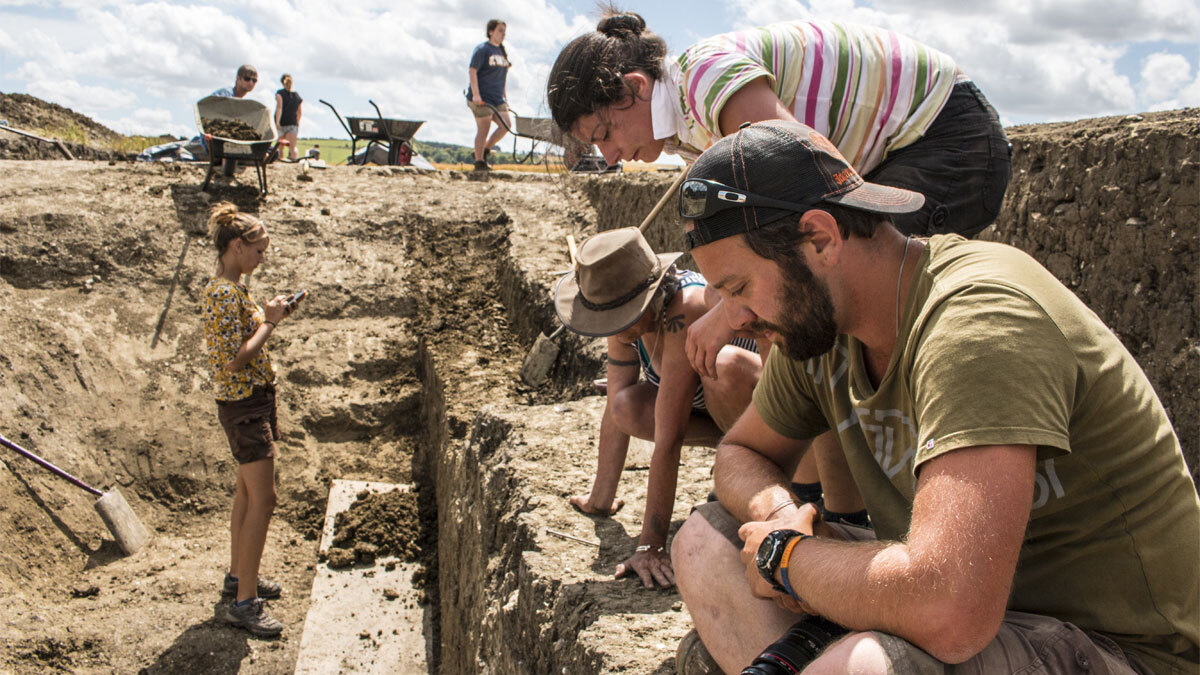 People gathered on a trench at an excavation site