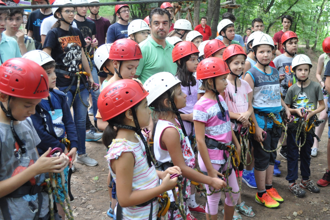 A group of young people outside in a forrest, wearing helmets and other safety gear.