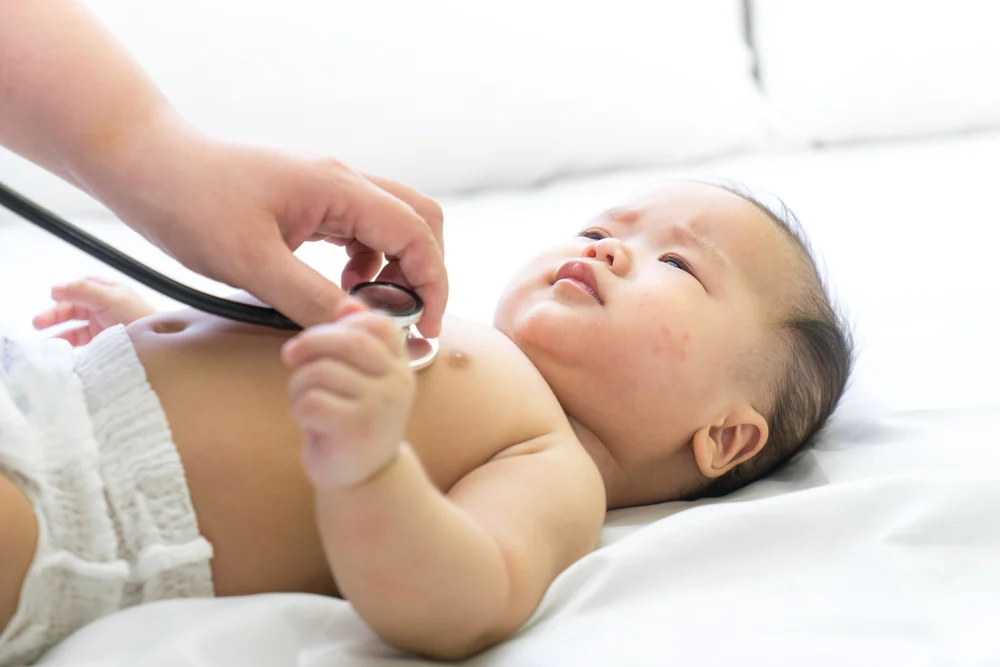 A beautiful Asian newborn is being examined with a stethoscope.