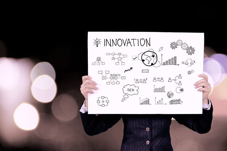 An entrepreneur holds up a piece of paper with 'innovation' written on it and a series of diagrams and graphs